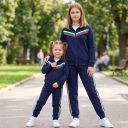 Съчетанието от спортна горница с цип и дълго долнище с цветни кантове придава модерна и динамична визия